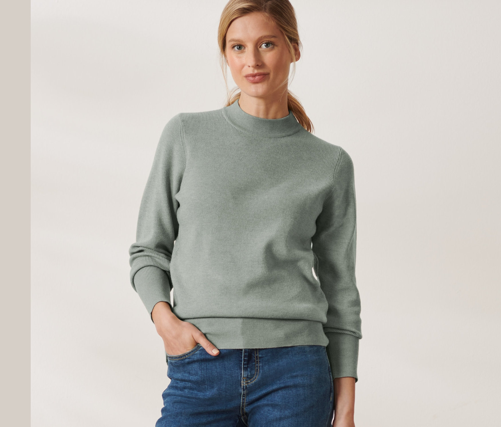 Frau trägt einen Strickpullover und Jeans.