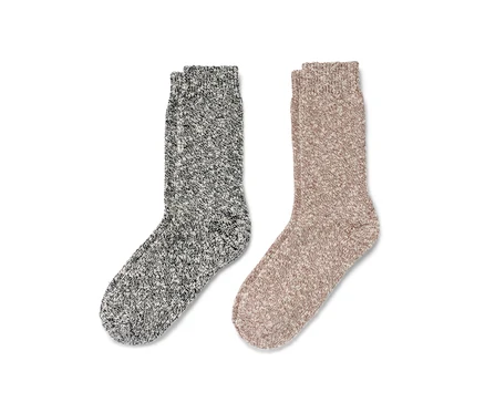 Zwei Paar Stricksocken liegen nebeneinander, eins grau und eins beige.