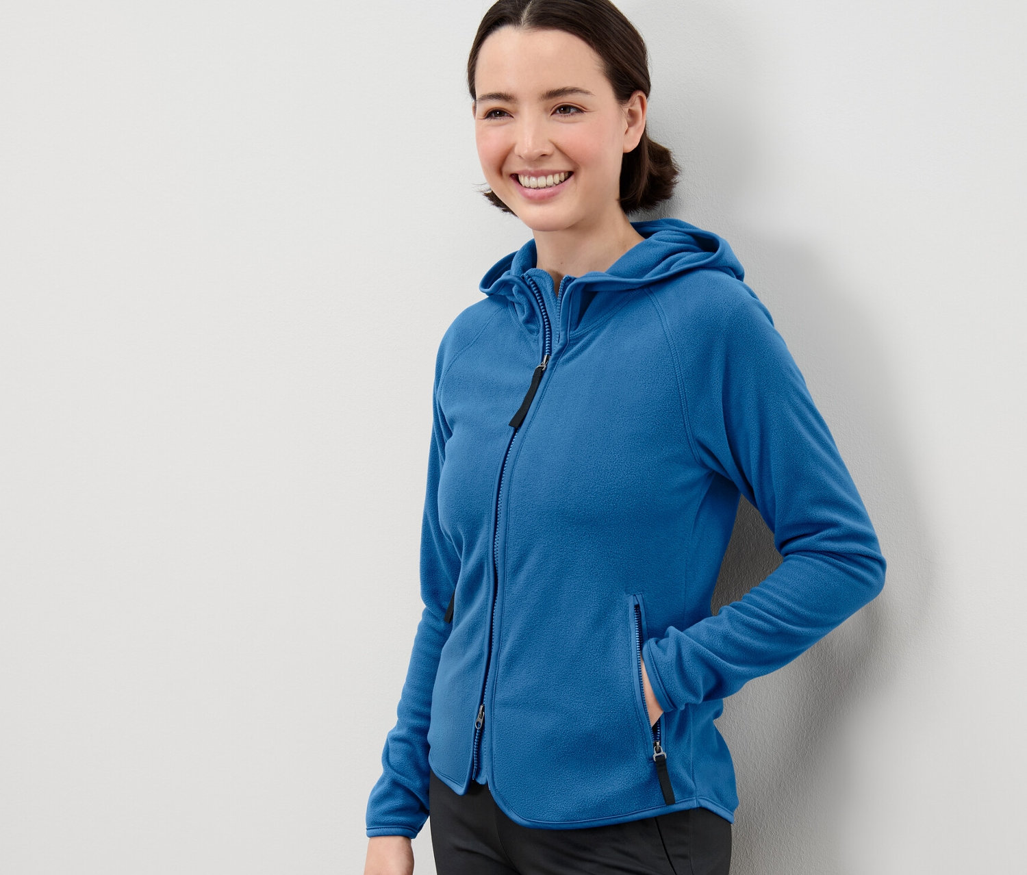 Frau posiert in blauer Kapuzen-Fleecejacke.