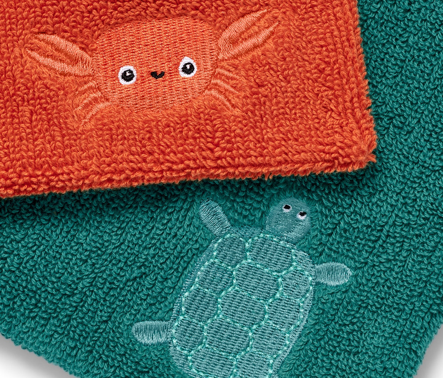Zwei Waschlappen: ein orangefarbener mit einer Krabbe und ein türkisfarbener mit einer Schildkröte.