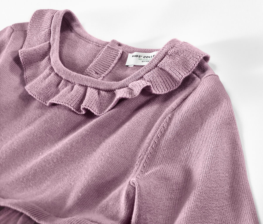Detailaufnahme eines Kinder-Strickkleids mit Rüschenkragen.