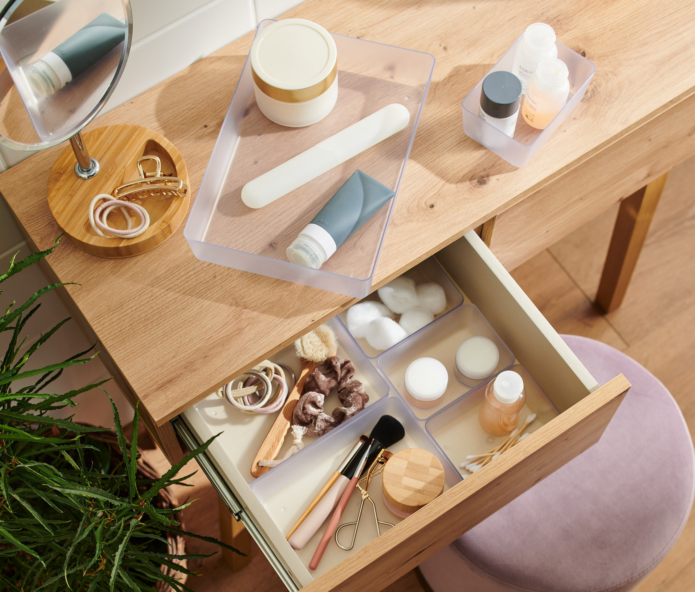 Eine geöffnete Schublade eines hölzernen Schminktisches enthält ein Schubladen-Organizer-Set mit Kosmetika.