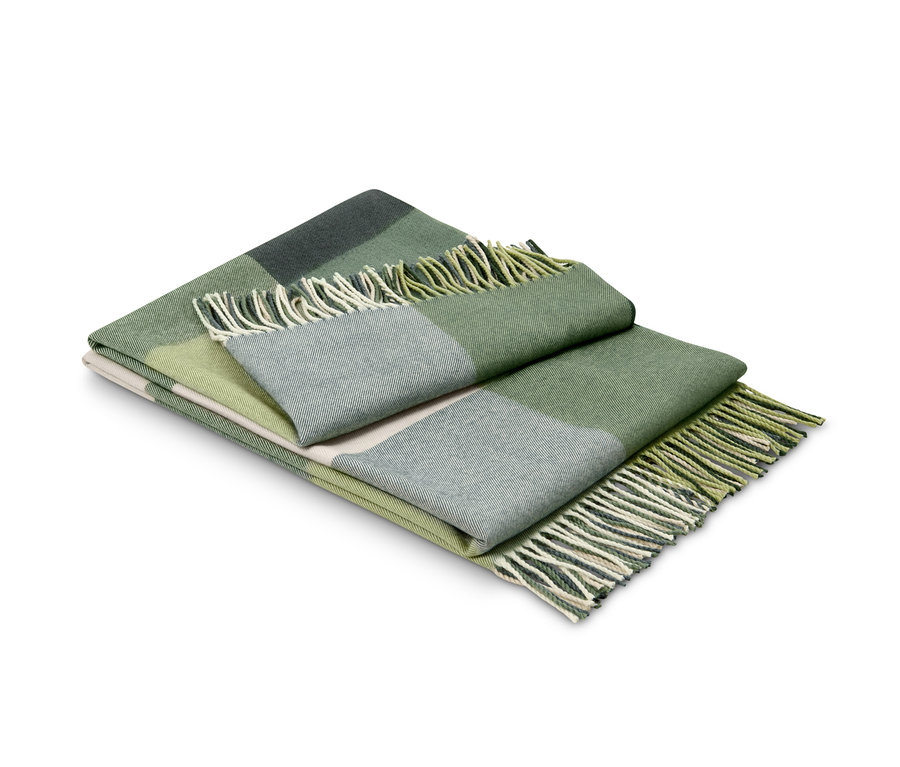 Ein gefalteter, grün karierter Plaid mit Fransen.