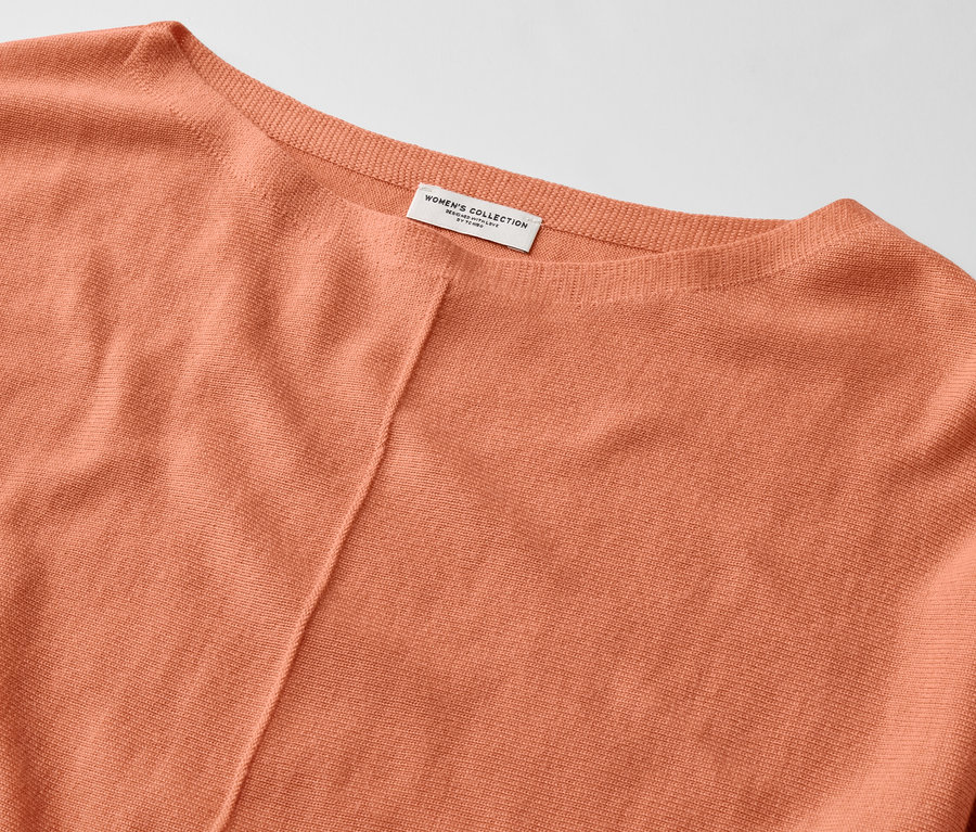 Detailaufnahme eines peachfarbenen Merino-Feinstrickpullovers.