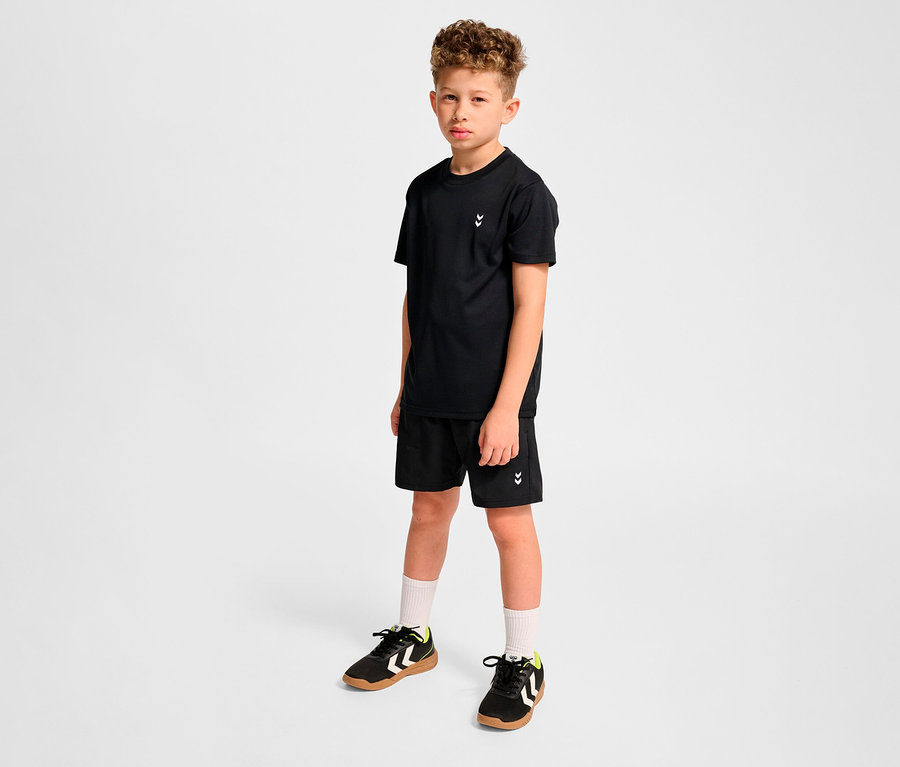 Junge posiert in schwarzem T-Shirt und schwarzen HUMMEL HMLJR Pulse Workout Shorts.