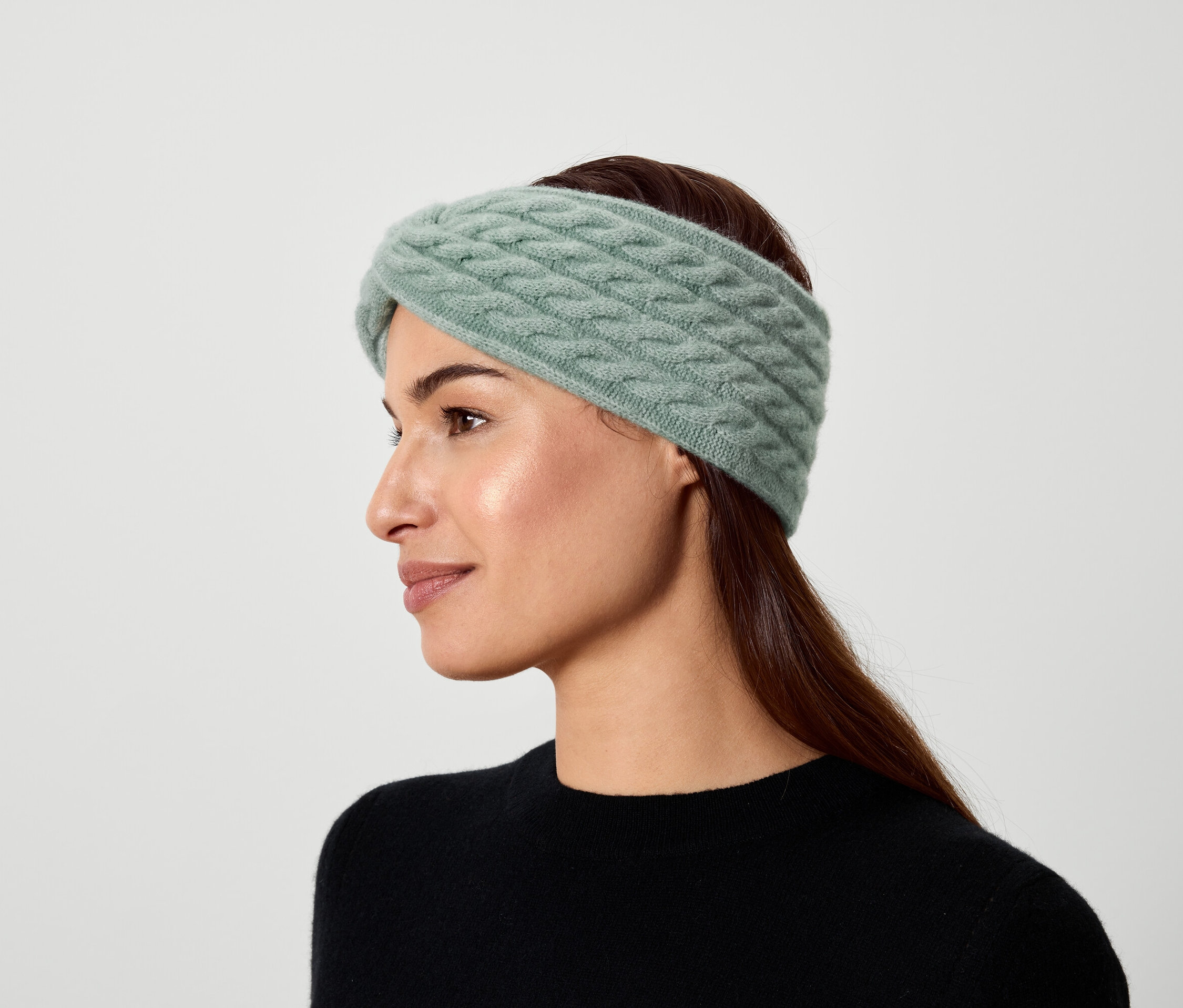 Porträt einer Frau mit braunen Haaren, die ein hellgrünes Strickstirnband trägt.