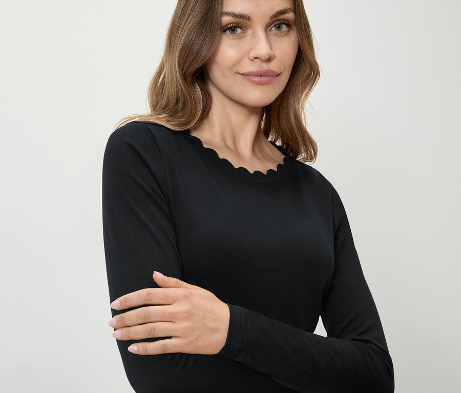 Frau trägt ein schwarzes Langarmshirt mit dekorativem Saum.