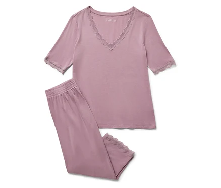 Ein lilafarbener Pyjama mit Spitze auf weißem Hintergrund.
