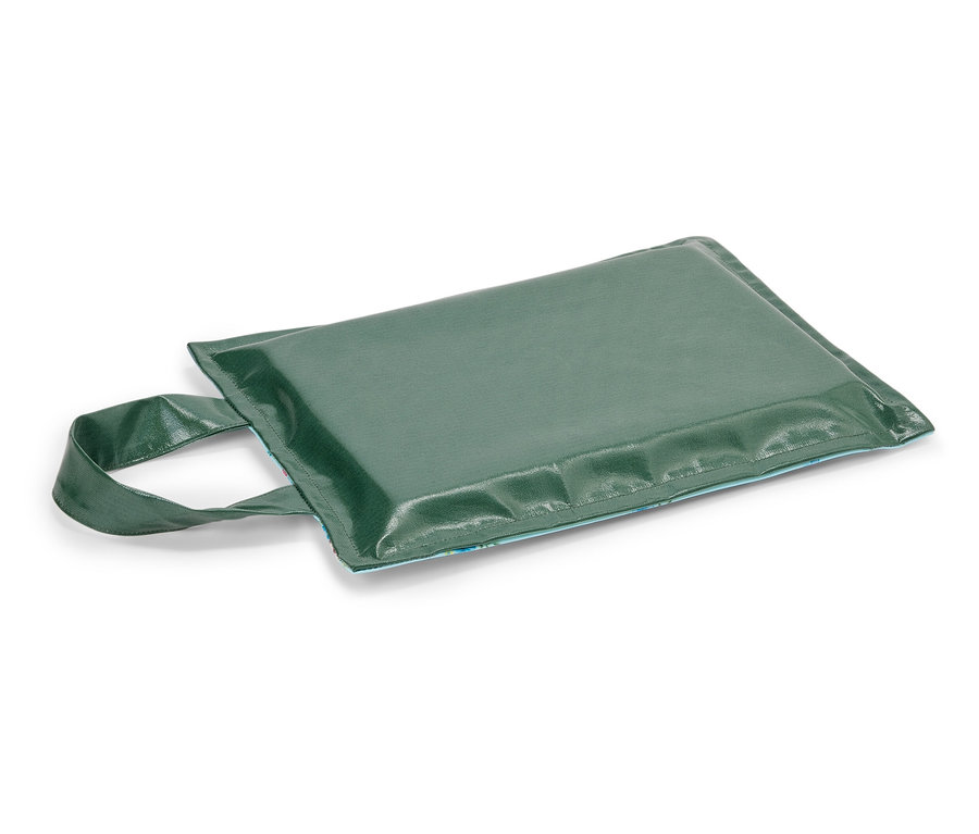 Grünes Sitzkissen mit Tragegriff liegt auf weißem Untergrund.