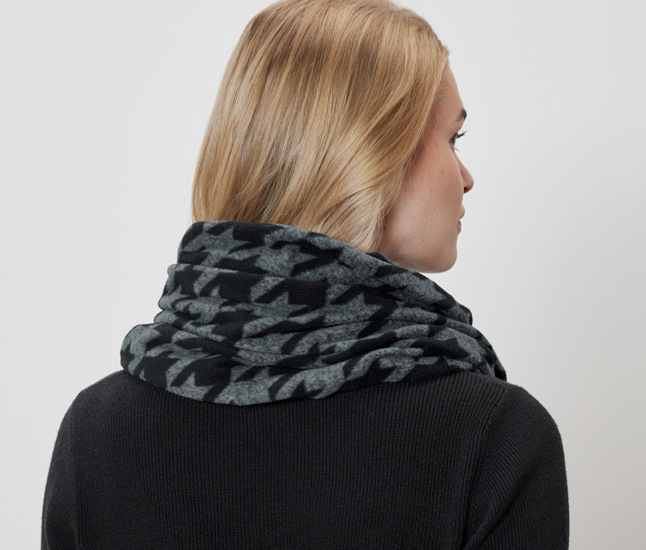 Frau trägt einen grau-schwarzen Hahnentritt-Schal und einen schwarzen Pullover.