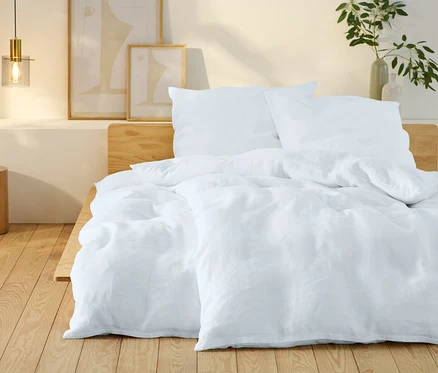 Weiße Leinen-Bettwäsche in Übergröße auf einem Bett.