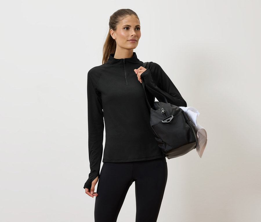 Frau in schwarzer Sportbekleidung mit einer Tasche über der Schulter.