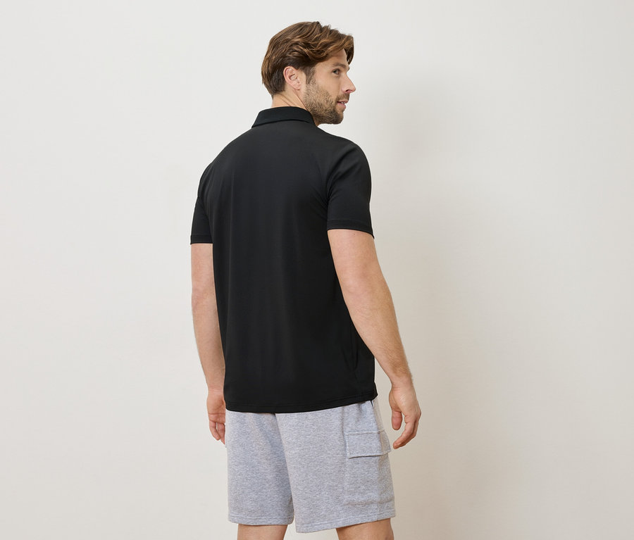 Mann von hinten mit schwarzem Poloshirt und grauer Shorts.