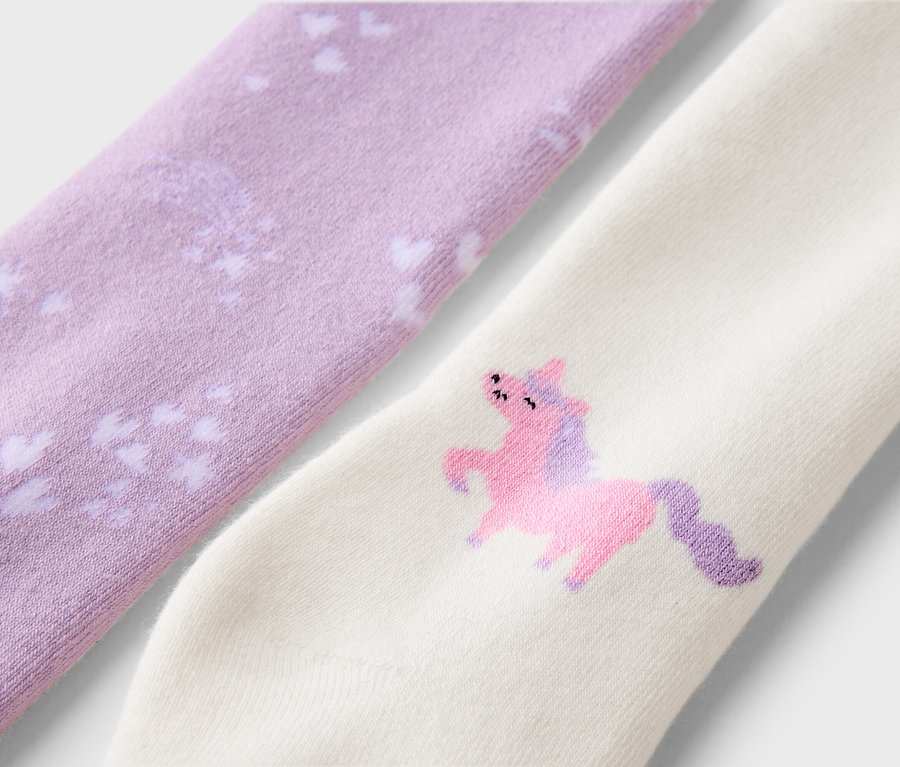 Nahaufnahme von zwei Socken, eine lavendelfarben mit weißen Herzen, die andere cremefarben mit einem rosa Einhorn.