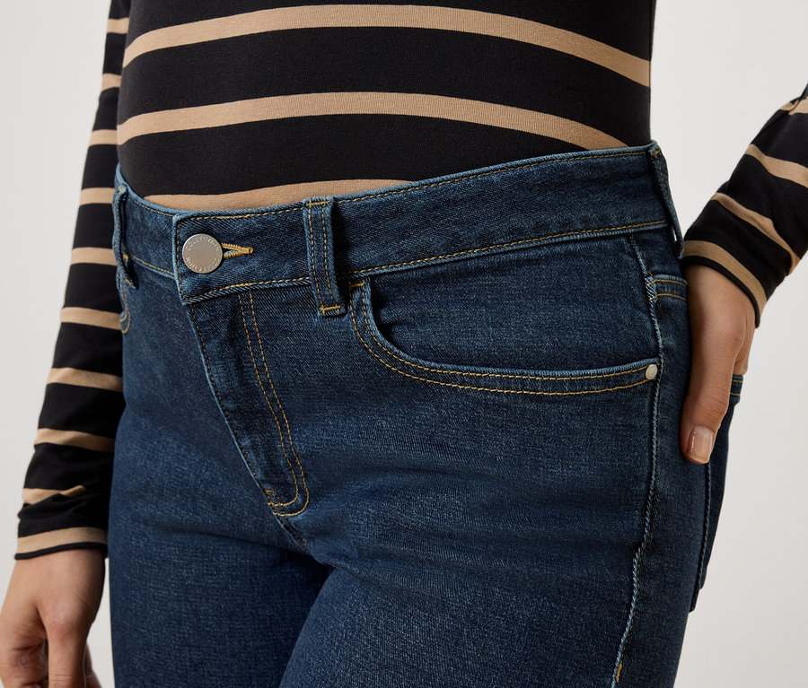 Nahaufnahme einer Frau in dunkelblauen Jeans und einem gestreiften Oberteil.