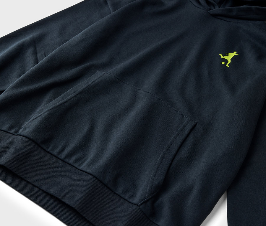 Nahaufnahme eines dunkelblauen Hoodies mit einer einzelnen aufgesetzten Tasche und einem hellgrünen Logo einer Fußball spielenden Person.