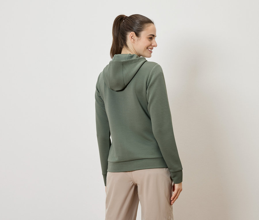 Frau von hinten, trägt einen olivgrünen Hoodie und beigefarbene Shorts.