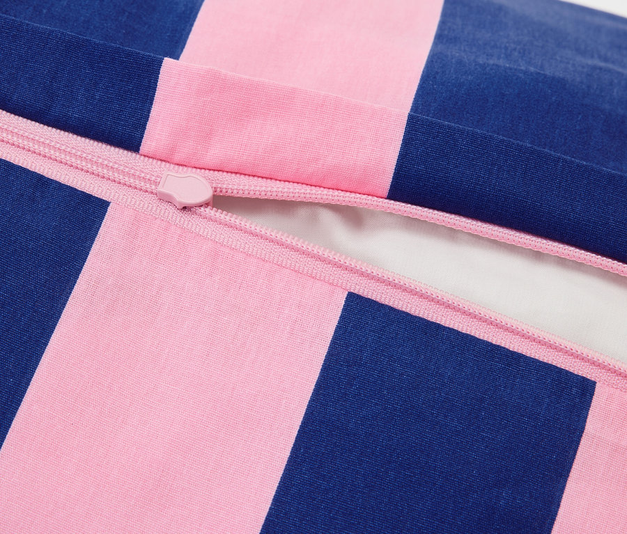 Nahaufnahme eines teilweise geöffneten Kissenbezugs mit rosa Reißverschluss und blau-rosa Streifen.