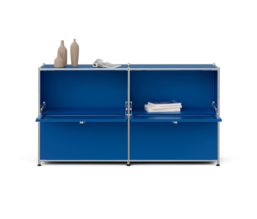 Blauer modularer Schrank mit Chromrahmen, zwei offenen Klapptüren und Dekoration. Links drei Vasen und eine Zeitschrift, rechts drei Bücher.