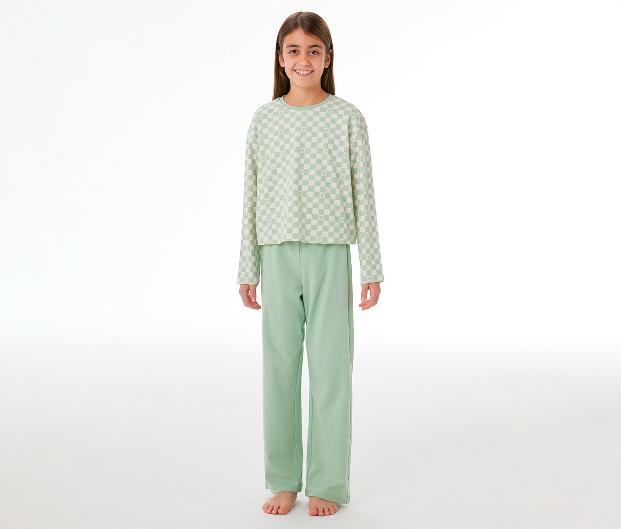 Lächelndes Mädchen in einem SCHIESSER Kinder-Interlock-Pyjama. Das Oberteil ist hellgrün-weiß kariert, die Hose hellgrün.