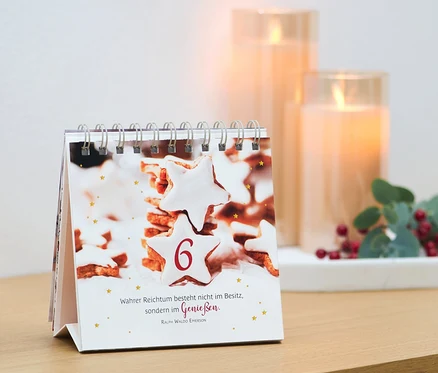 Ein Tischkalender mit einem Bild von Keksen und der Zahl 6, daneben Kerzen und Dekoration. Buch/Aufsteller: »Adventszauber«