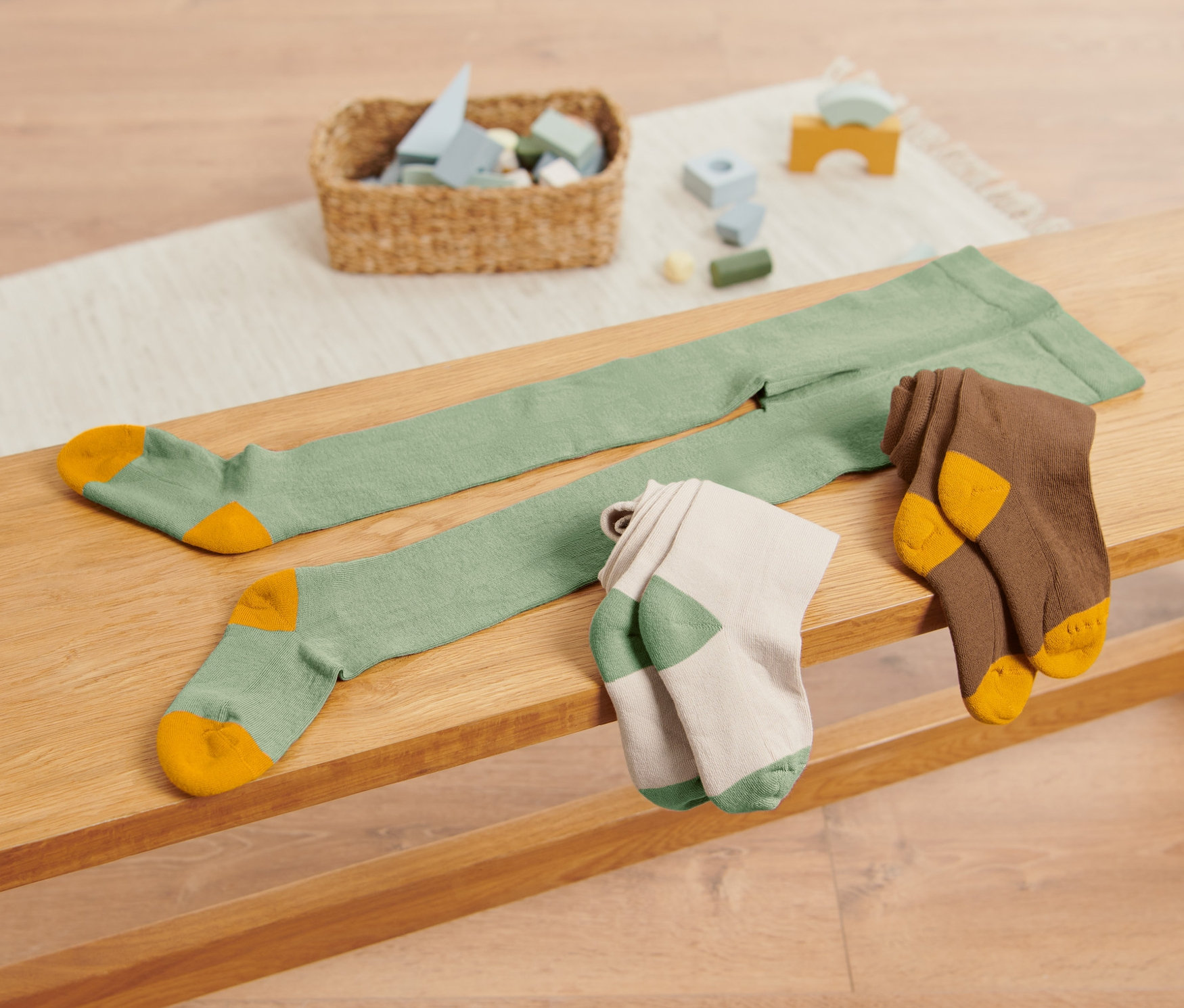 Auf einer Bank liegen 3 Paar grüne Strumpfhosen.