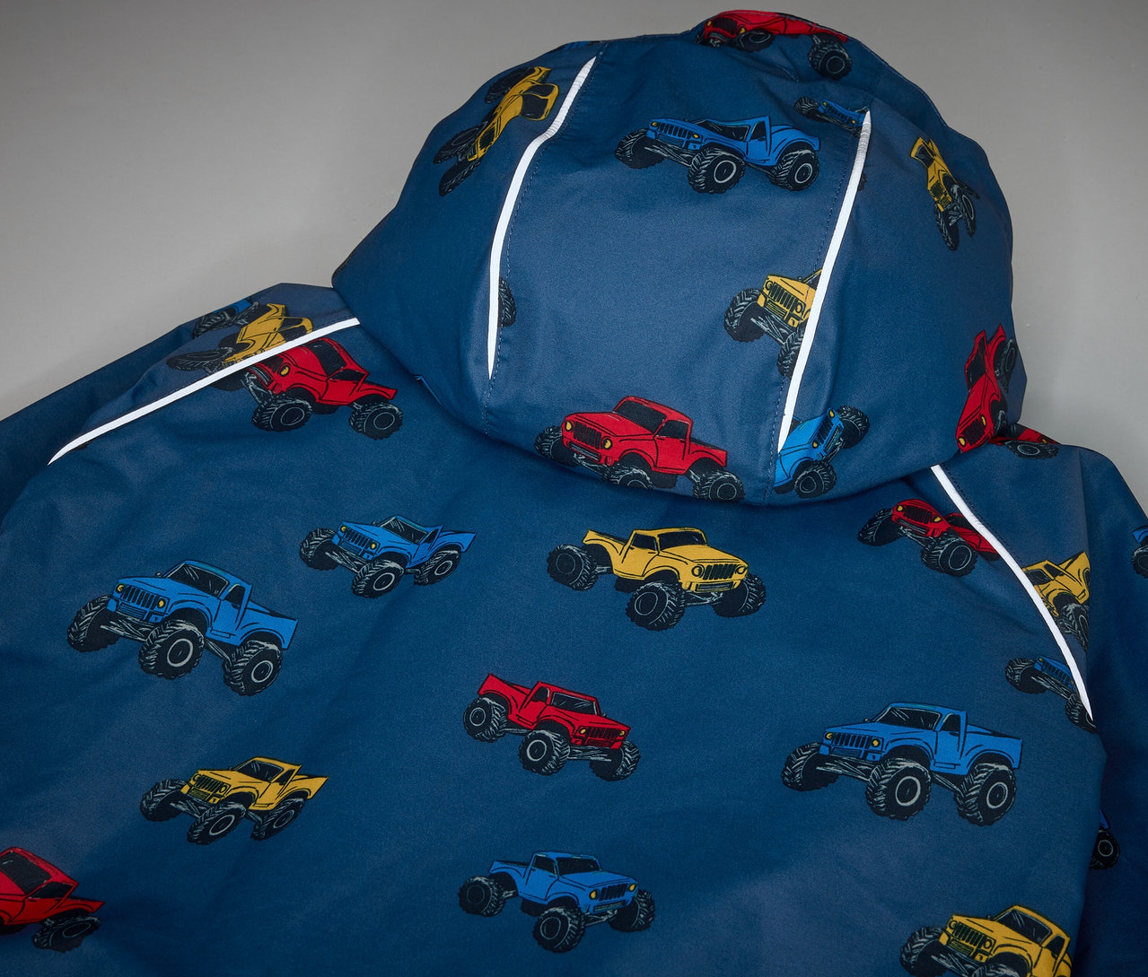 Detailansicht einer Kinder-Thermo-Regenjacke mit Monstertruck-Muster.