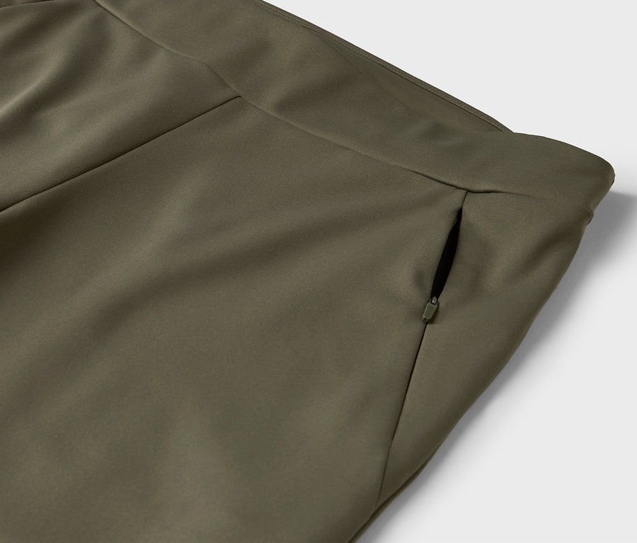 Detail einer olivgrünen Hose mit Reißverschlusstasche.