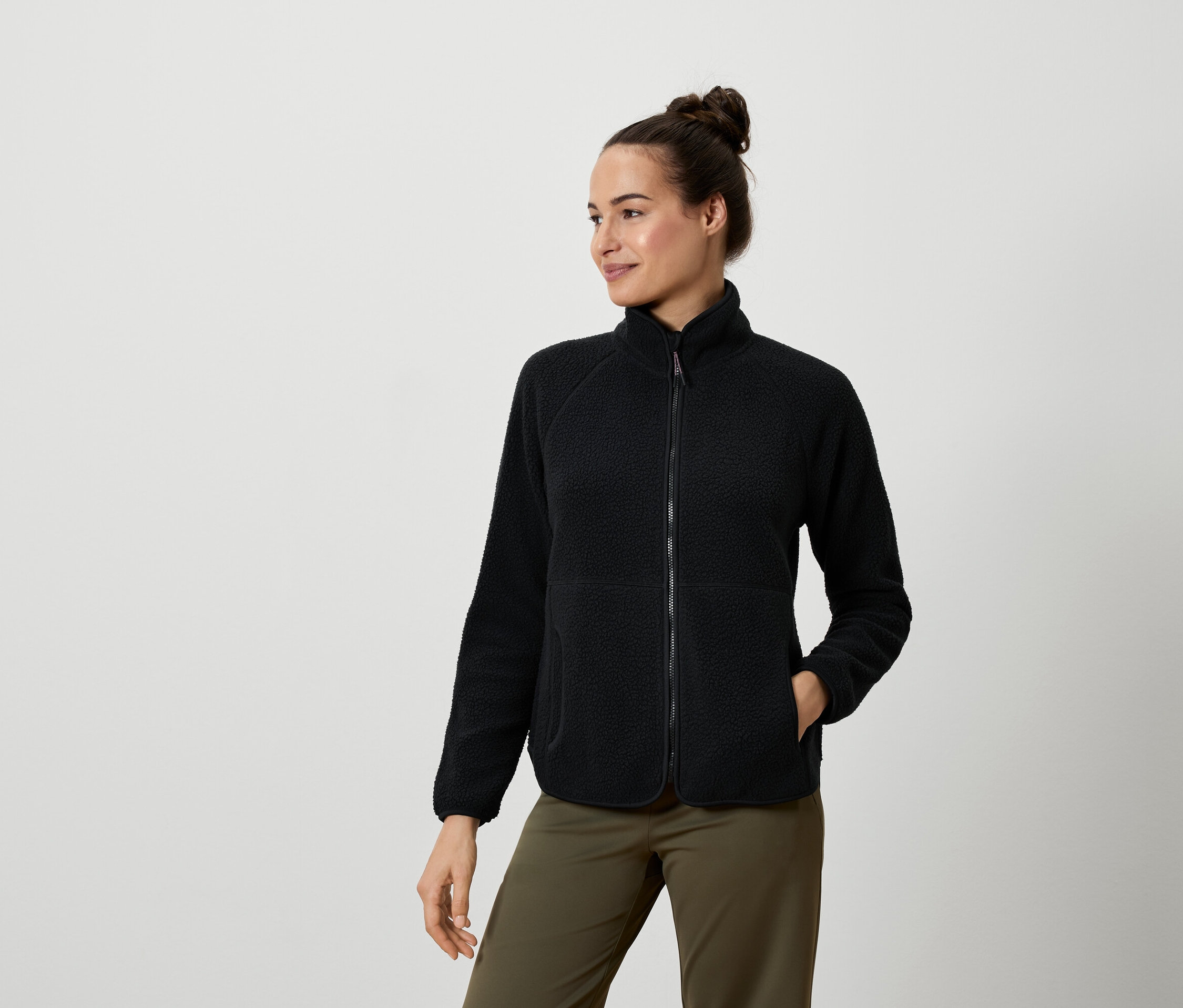 Frau trägt eine schwarze Fleecejacke und olivgrüne Hosen.