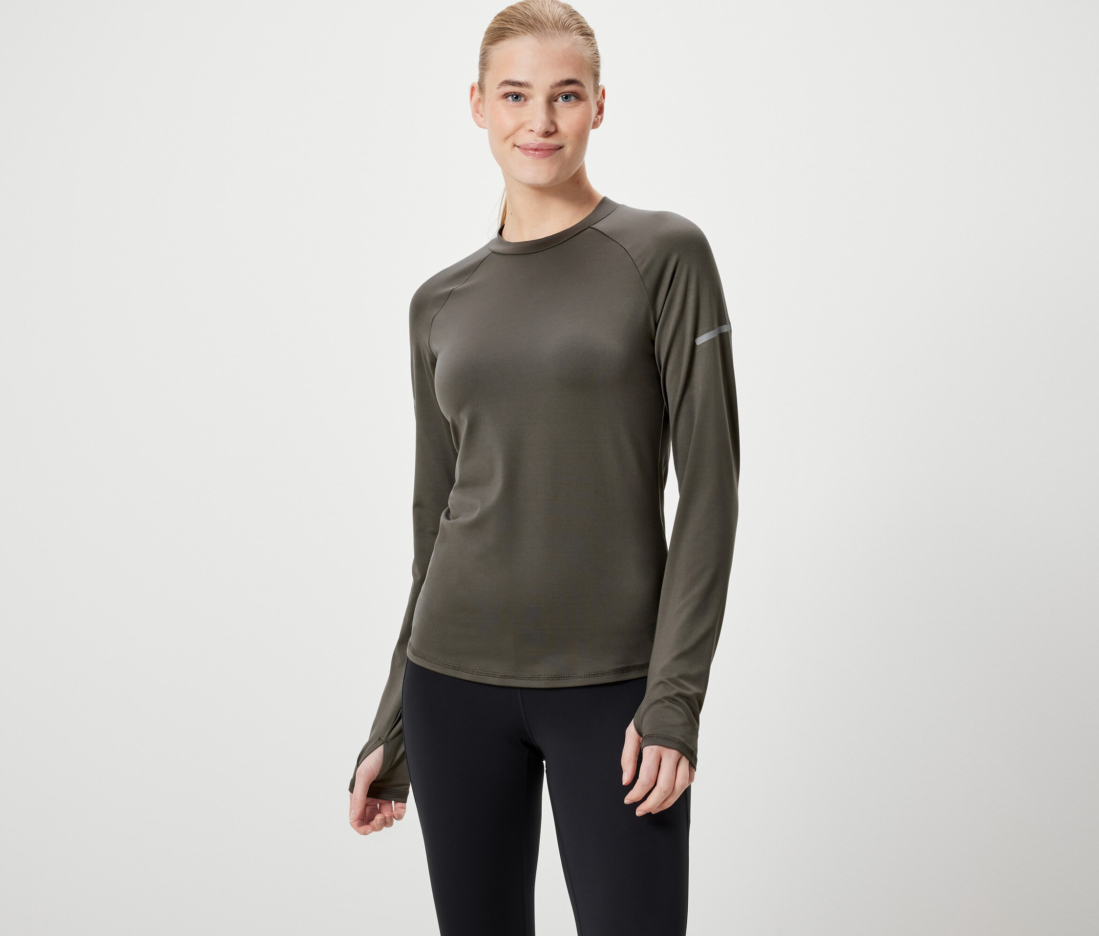 Frau trägt ein olivgrünes Langarmshirt und schwarze Leggings.