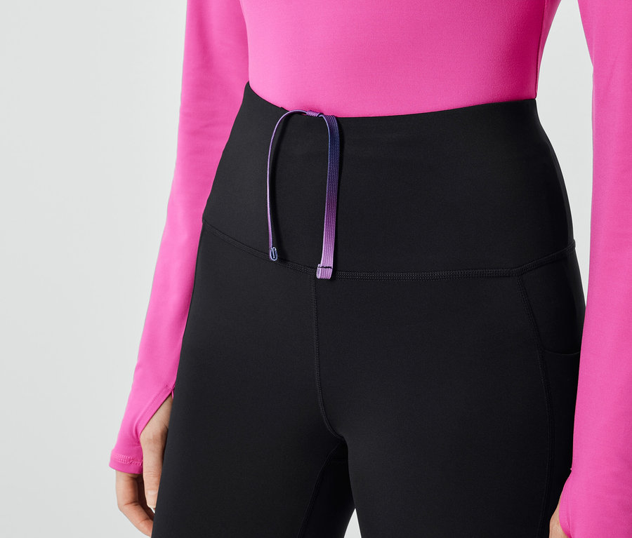 Detailaufnahme von schwarzen Damen Leggings mit lila Kordelzug und pinkem Oberteil.
