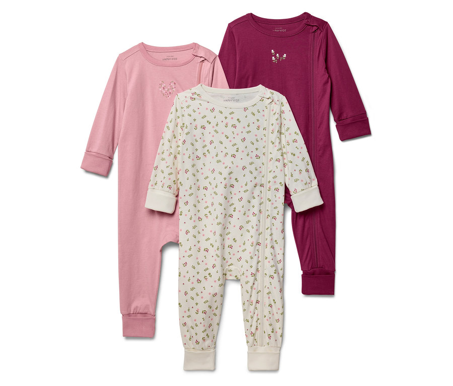 Drei Baby-Schlafanzüge liegen aufgereiht da: ein rosa, ein weißer mit Blumenmuster und ein weinroter.