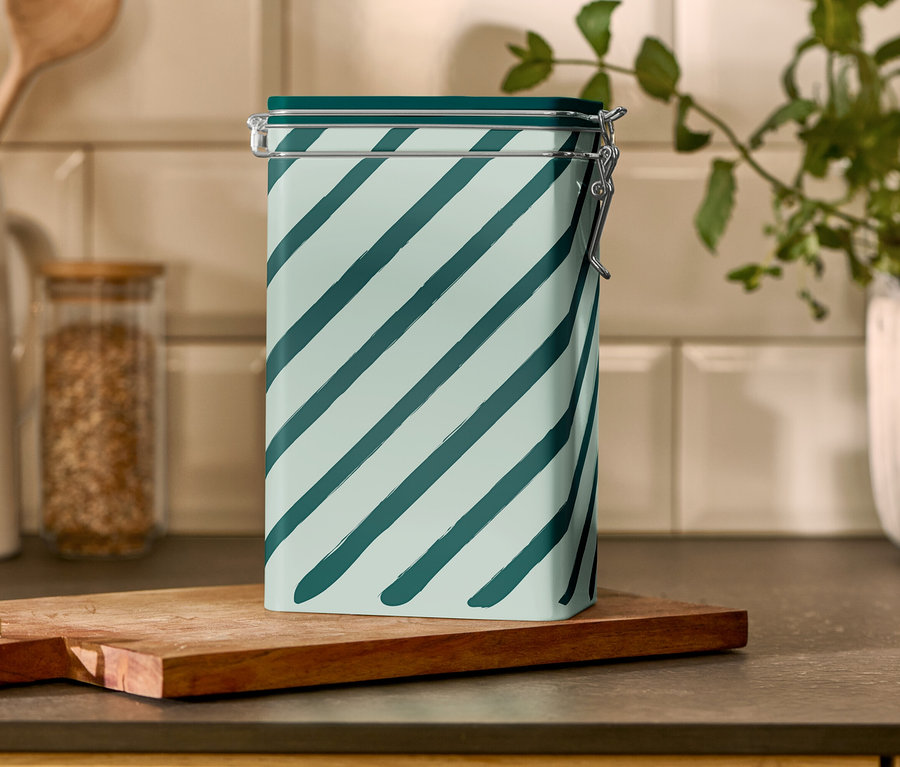 Eine gestreifte Kaffeedose steht auf einem Holzbrett.