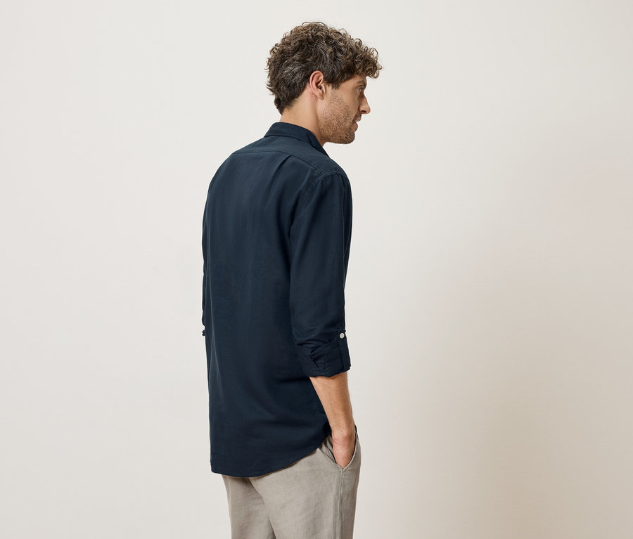 Mann von hinten in marineblauem Hemd und grauer Hose.