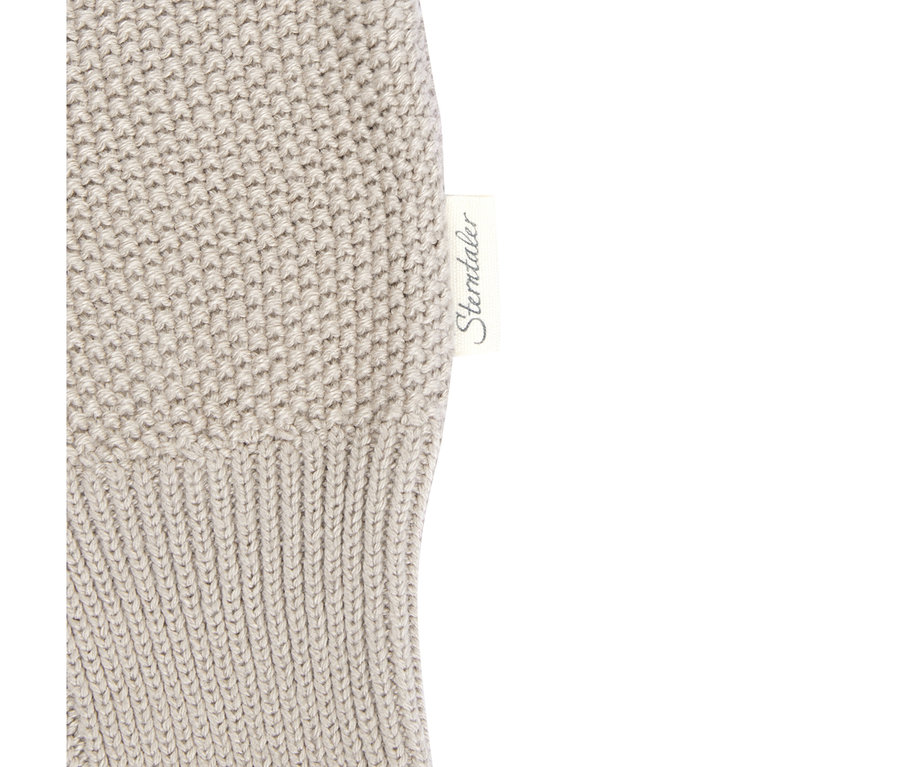 Nahaufnahme einer hellbeigen Sterntaler Baby-Strickhose, die ein weißes Markenetikett mit dem Schriftzug „Sterntaler“ auf einem gerippten Strickabschnitt neben einem dichteren Strickabschnitt zeigt.
