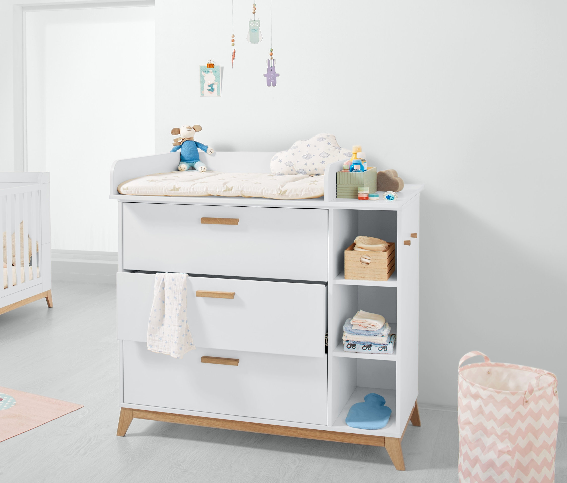 Weiße Wickelkommode mit drei Schubladen und offenen Regalen.