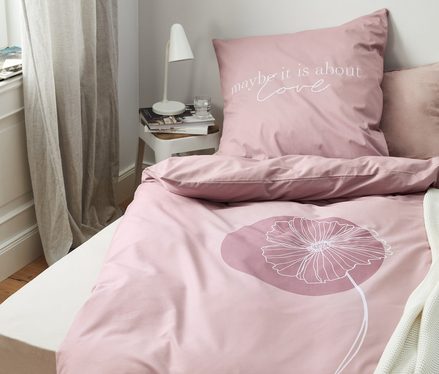 Rosa Perkal-Bettwäsche mit Blumenmuster und dem Schriftzug "maybe it is about love" auf dem Kissen.