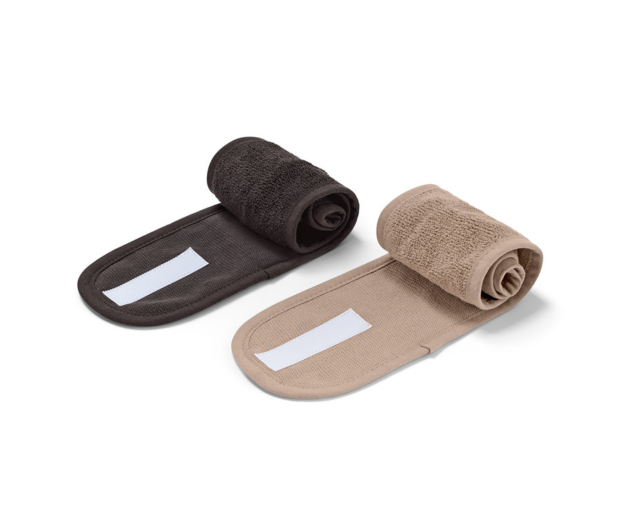 Zwei Kosmetik-Stirnbänder, schwarz und braun, gerollt auf einem weißen Hintergrund.