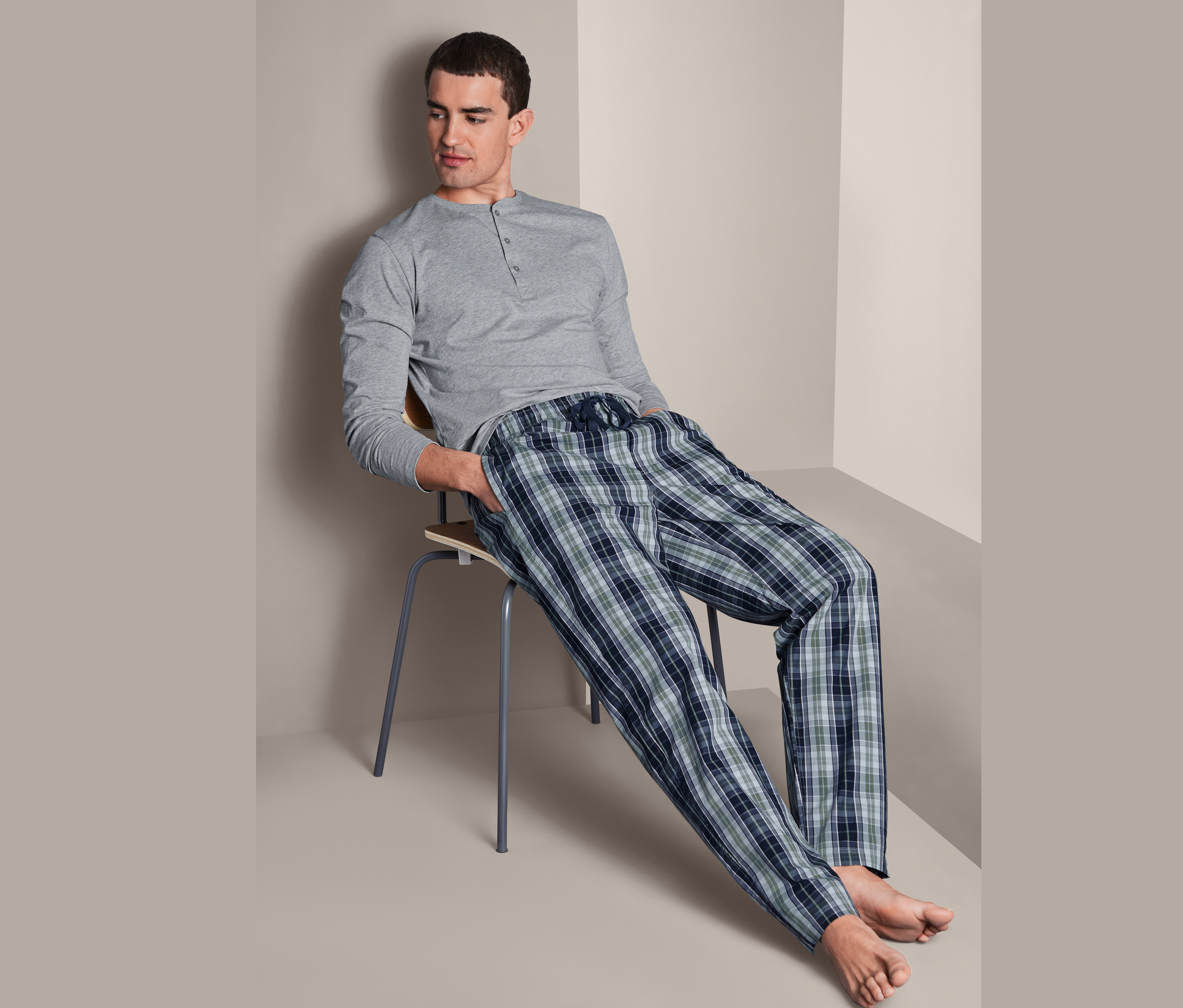 Mann sitzt auf einem Stuhl und trägt einen Pyjama.