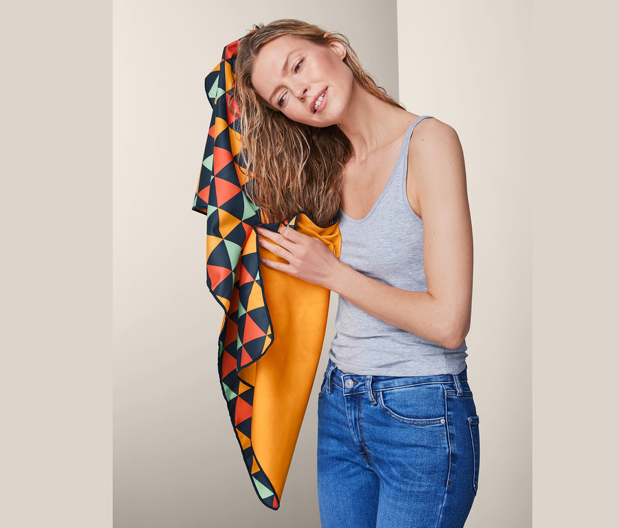 Frau trocknet ihre Haare mit einem mehrfarbigen Outdoor-Handtuch, ca. 50 x 100 cm.
