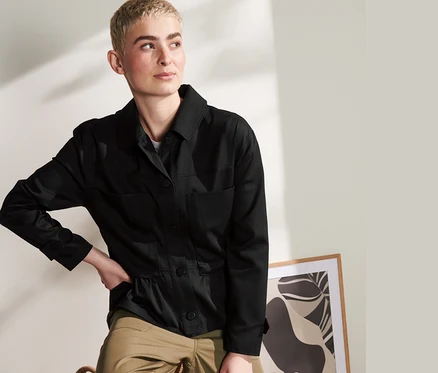 Frau posiert in schwarzem Overshirt und Khaki-Hosen.