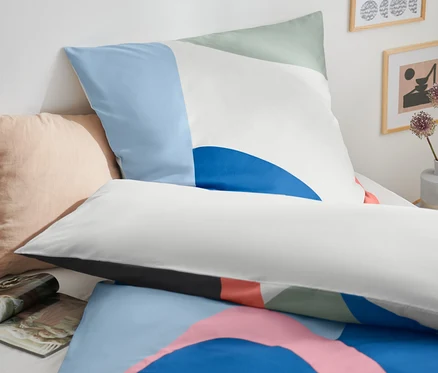 Detailansicht von Premium-Baumwoll-Bettwäsche in Normal- und Übergröße mit geometrischem Muster in Blau, Grün und Rosa.