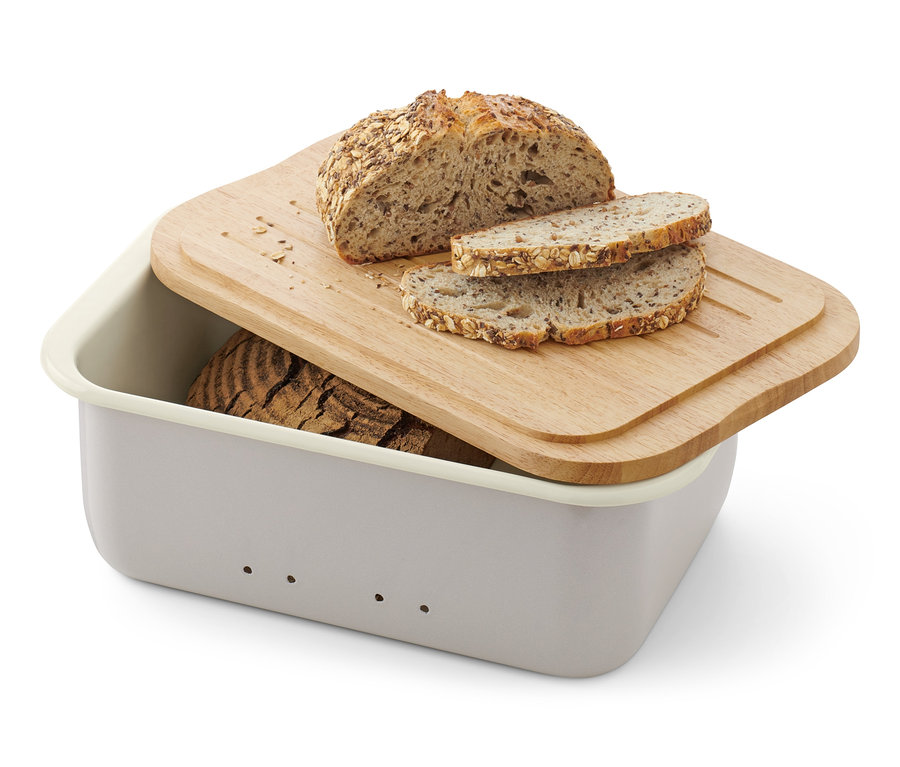 Halbes Brot und zwei Scheiben auf dem Emaille-Brotkasten mit Schneidebrett.