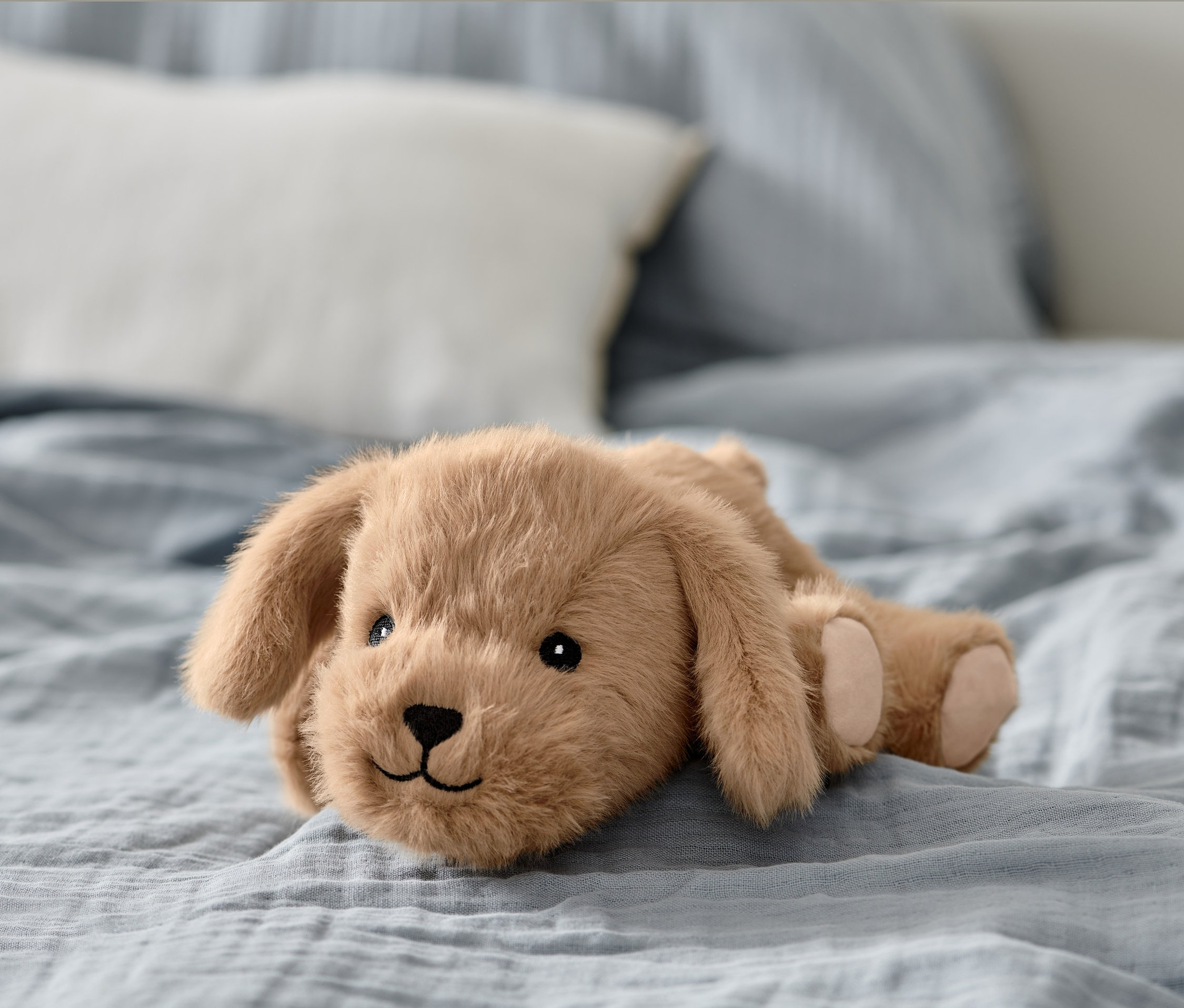Ein Plüschtier »Hund« liegt auf einem Bett.