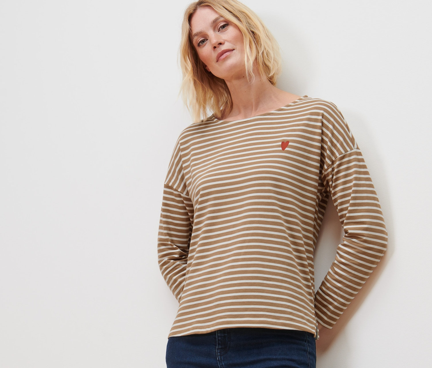 Frau trägt ein gestreiftes Langarmshirt und Jeans.