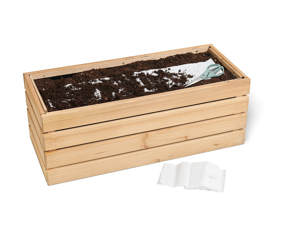 Holzkübel mit Erde, einem Saatteppich und einer Schere. Ein »Bienenwiese« Saatteppich liegt im Kübel.