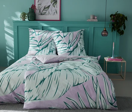 Bett mit Renforcé-Bettwäsche mit Blättermotiv.