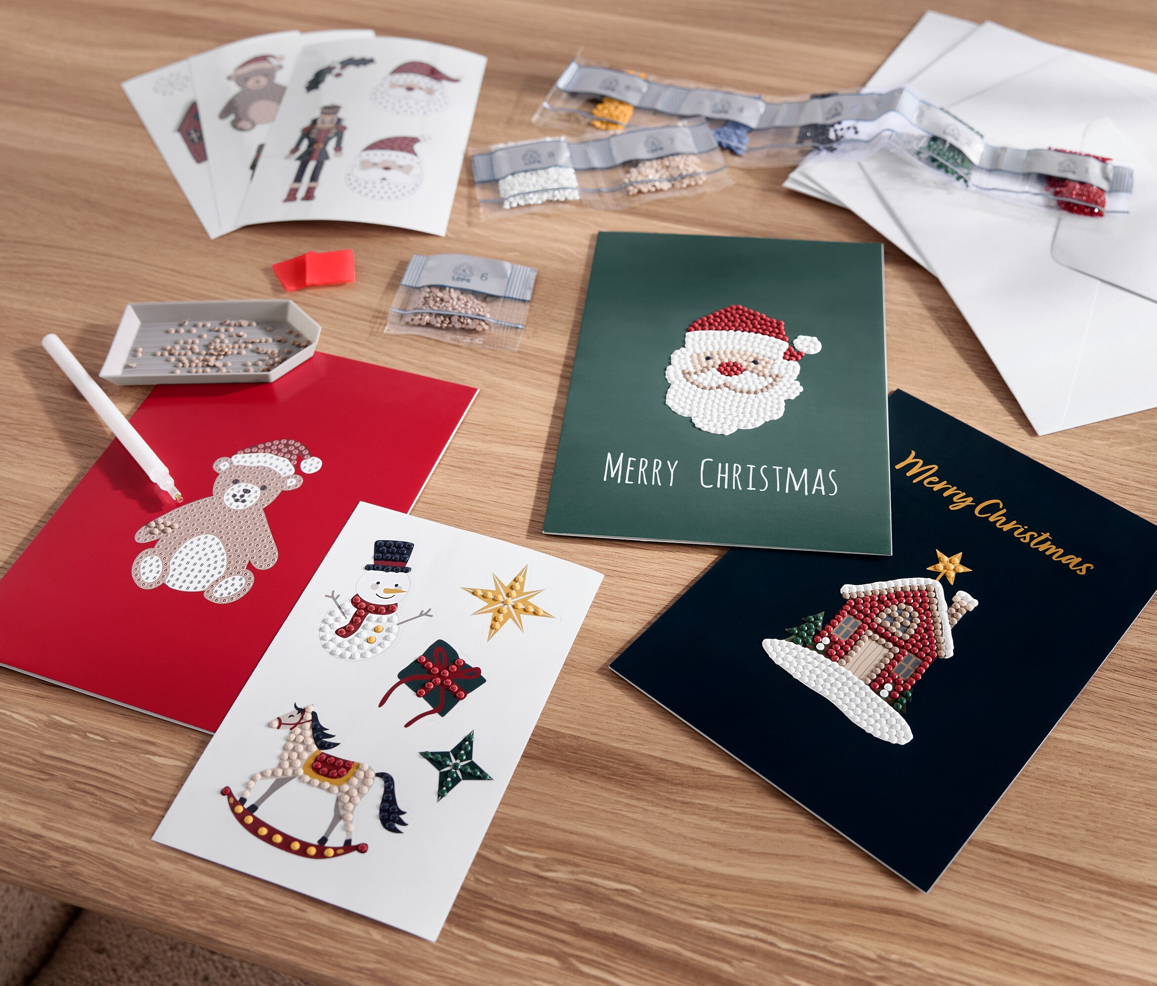 Ausgelegte Weihnachtskarten mit Motiven von Teddybär, Weihnachtsmann, Schneemann und Haus.