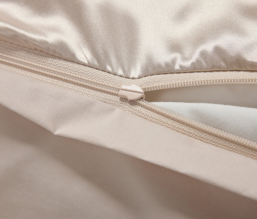 Detailaufnahme eines beigen Kissenbezugs mit Reißverschluss.