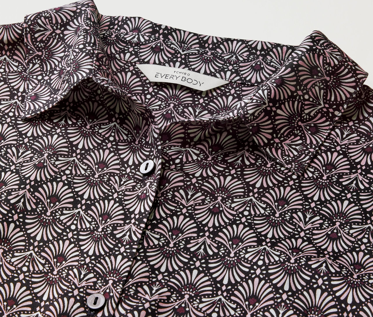 Detailansicht eines Web-Nachthemds mit schwarz-weißem Blumenmuster und Knöpfen.